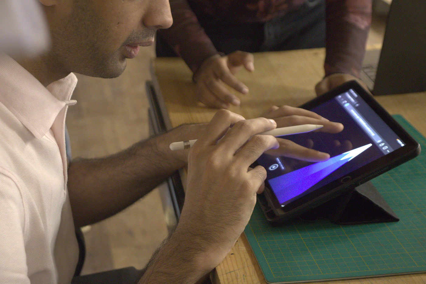 A user holding an Apple Pencil in one hand while exploring canvas boundaries with their other hand on an iPad running the Accessible Canvas interface.